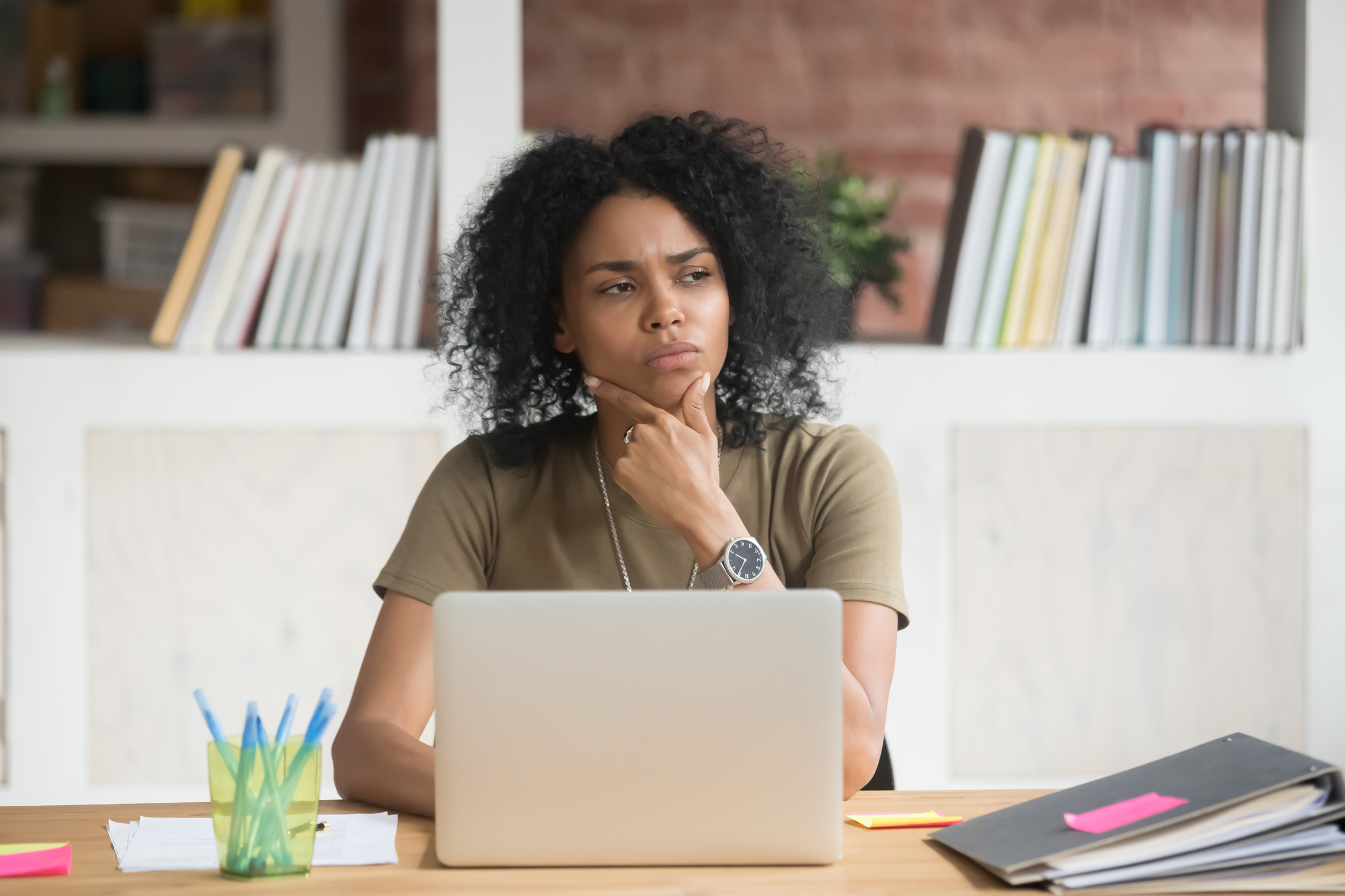 Thoughtful doubtful african worker feeling puzzled at work with laptop